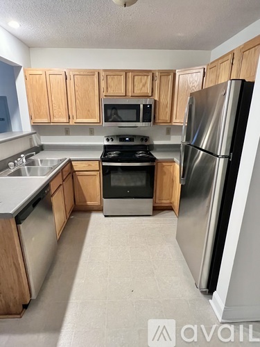 A kitchen with wooden cabinets and a stainless steel refrigerator.