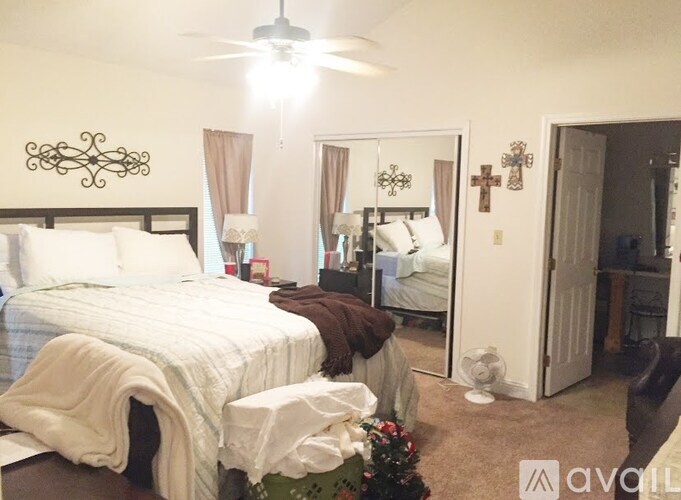 A bedroom with a large bed and a ceiling fan.