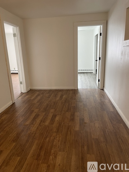 A room with wooden flooring and white walls.