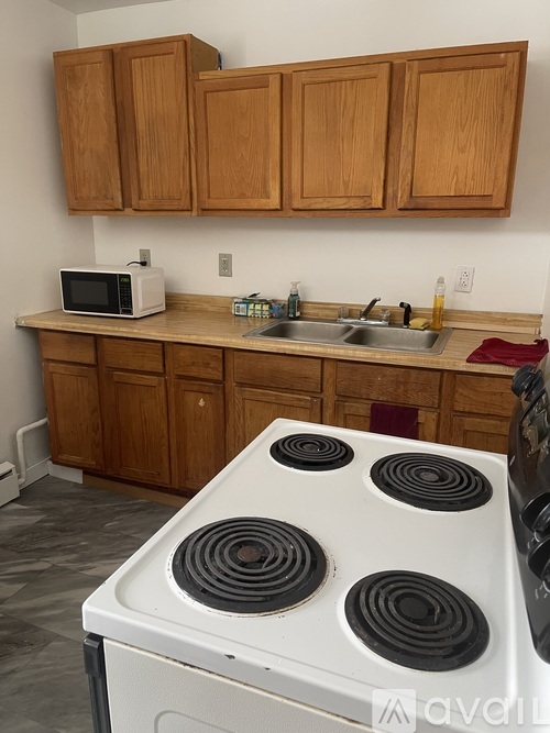 A kitchen with a white stove and wooden cabinets.