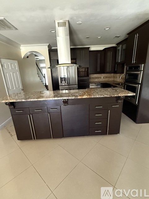 A kitchen with dark brown cabinets and a granite countertop.
