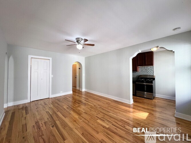 A spacious room with wooden floors and a ceiling fan.