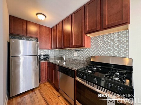 A kitchen with wooden cabinets and a stainless steel refrigerator.
