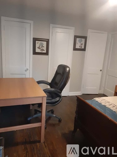A room with a desk, chair, and two pictures on the wall.