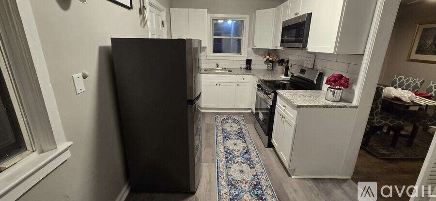 A kitchen with a black refrigerator and white cabinets.