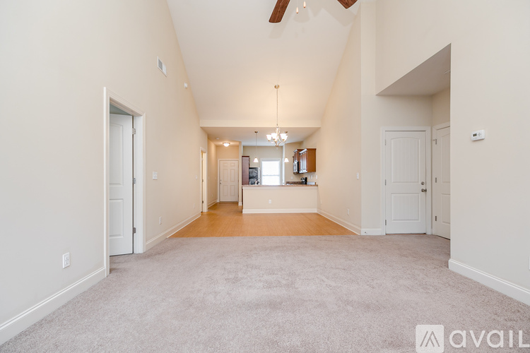A spacious living room with a carpeted floor and a chandelier hanging from the ceiling.
