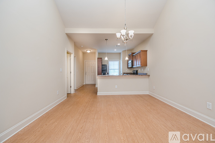 A spacious room with wooden floors and a chandelier hanging from the ceiling.