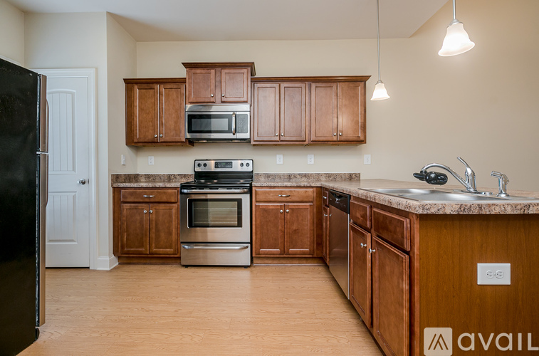 A kitchen with wooden cabinets and a black refrigerator.