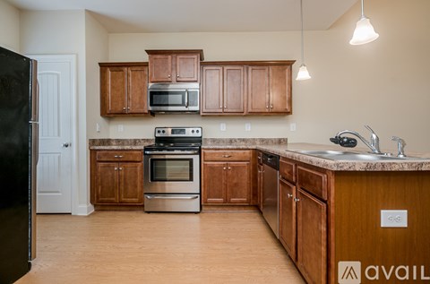 A kitchen with wooden cabinets and a black refrigerator.