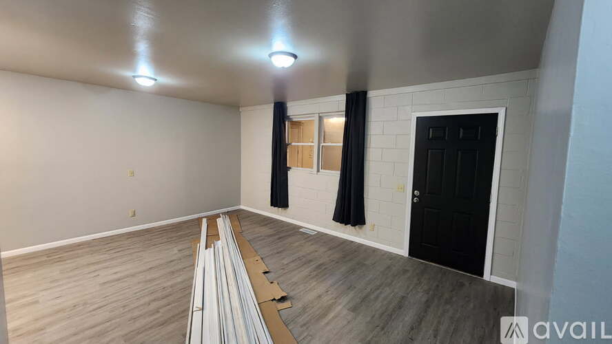 A room with a black door and a window with black curtains.