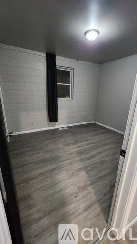 A room with a wooden floor and a window with a black frame.