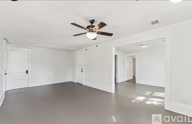 A spacious room with a ceiling fan and white walls.