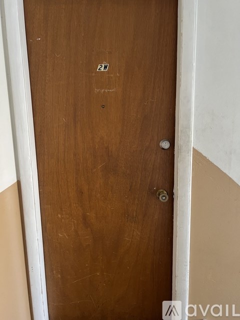 A brown door with a silver handle and a small sticker on it.