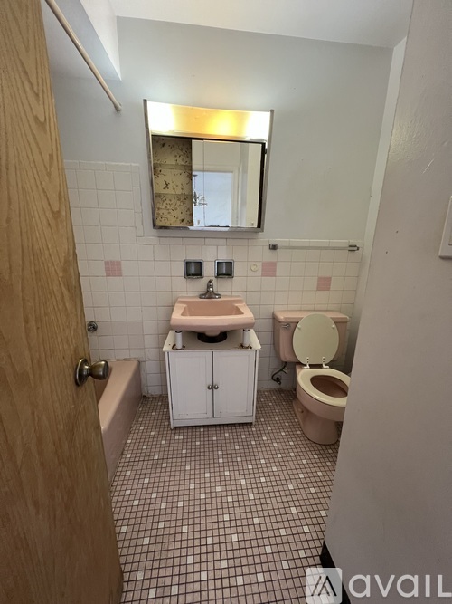 A bathroom with a toilet, sink, and mirror.
