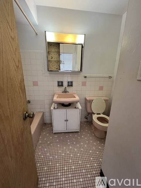 A bathroom with a toilet, sink, and mirror.