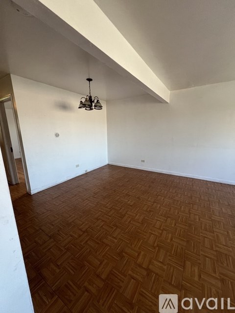 A room with wooden flooring and a chandelier hanging from the ceiling.