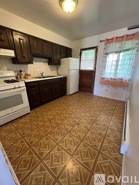 A kitchen with brown patterned flooring and white appliances.