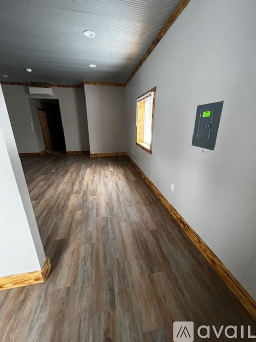 A room with wooden flooring and a wall socket on the wall.