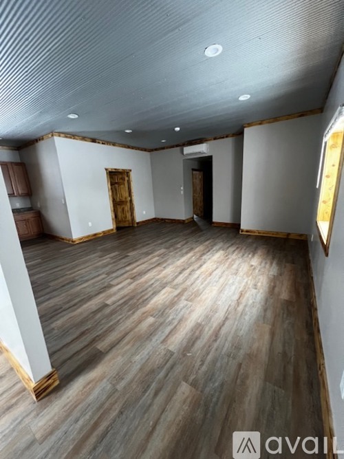 A room with wooden flooring and a white wall with a door.