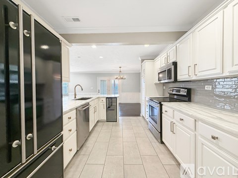 A kitchen with white cabinets and black appliances.