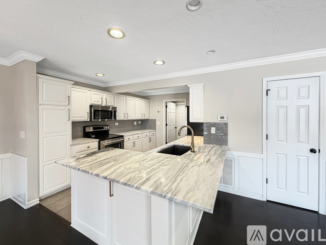 A kitchen with a marble countertop and white cabinets.