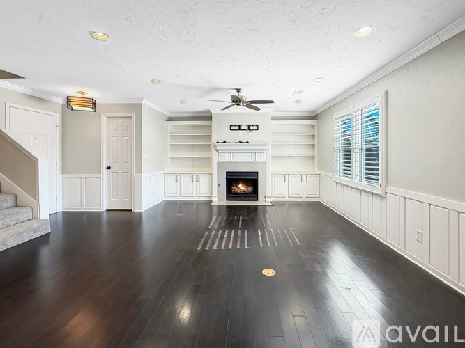 A spacious living room with a fireplace and a staircase.