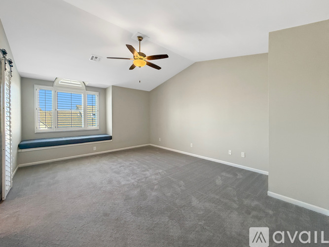A spacious room with a ceiling fan and a window with blinds.