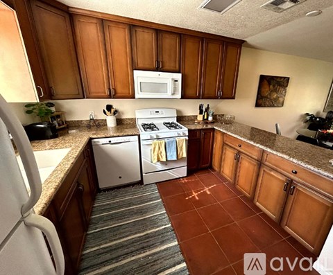 A kitchen with brown cabinets and a white fridge.