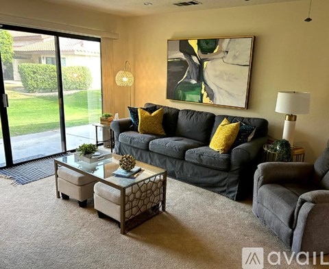 A living room with a grey couch, a coffee table, and a painting on the wall.
