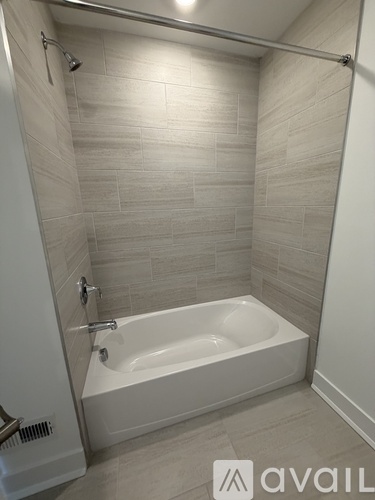 A white bathtub in a bathroom with tiled walls.