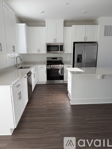 A kitchen with white cabinets and a wooden floor.