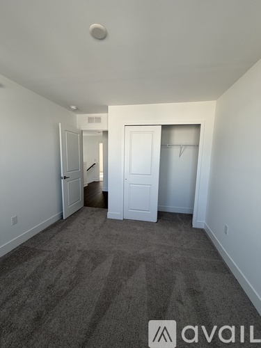 A carpeted room with a doorway leading to another room.