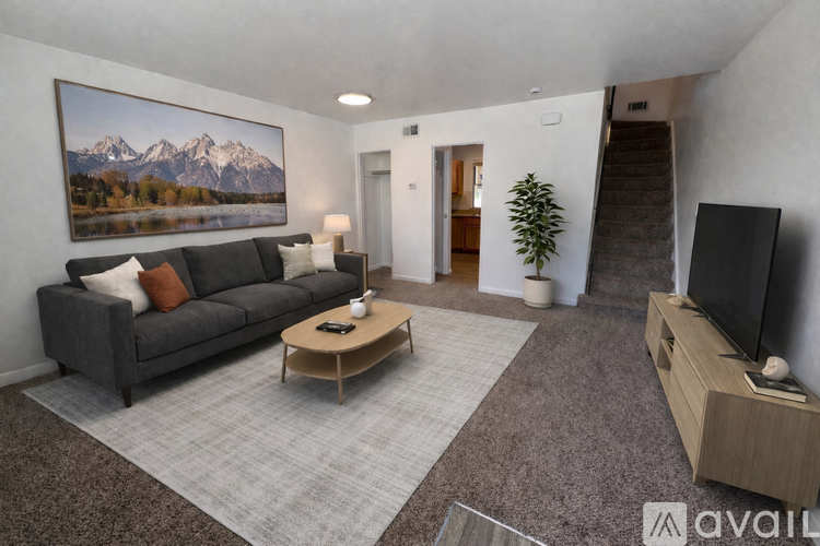 A living room with a grey couch, a wooden coffee table, and a large painting of mountains on the wall.