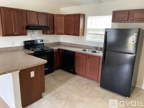 A kitchen with black appliances and brown cabinets.