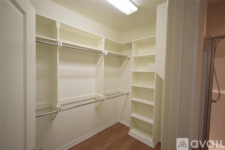 A walk-in closet with white shelving and a wooden floor.