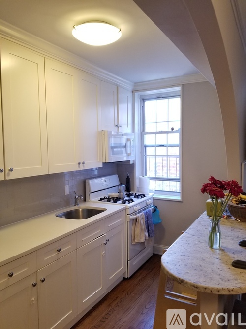A kitchen with white cabinets and a marble countertop.