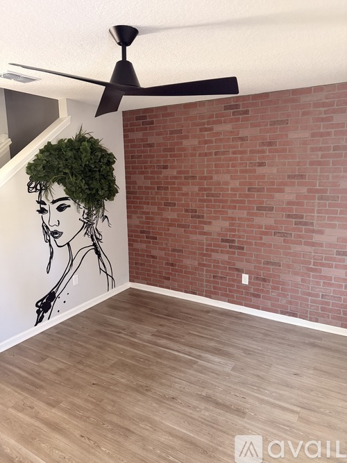 A room with a ceiling fan and a mural of a woman's face on the wall.