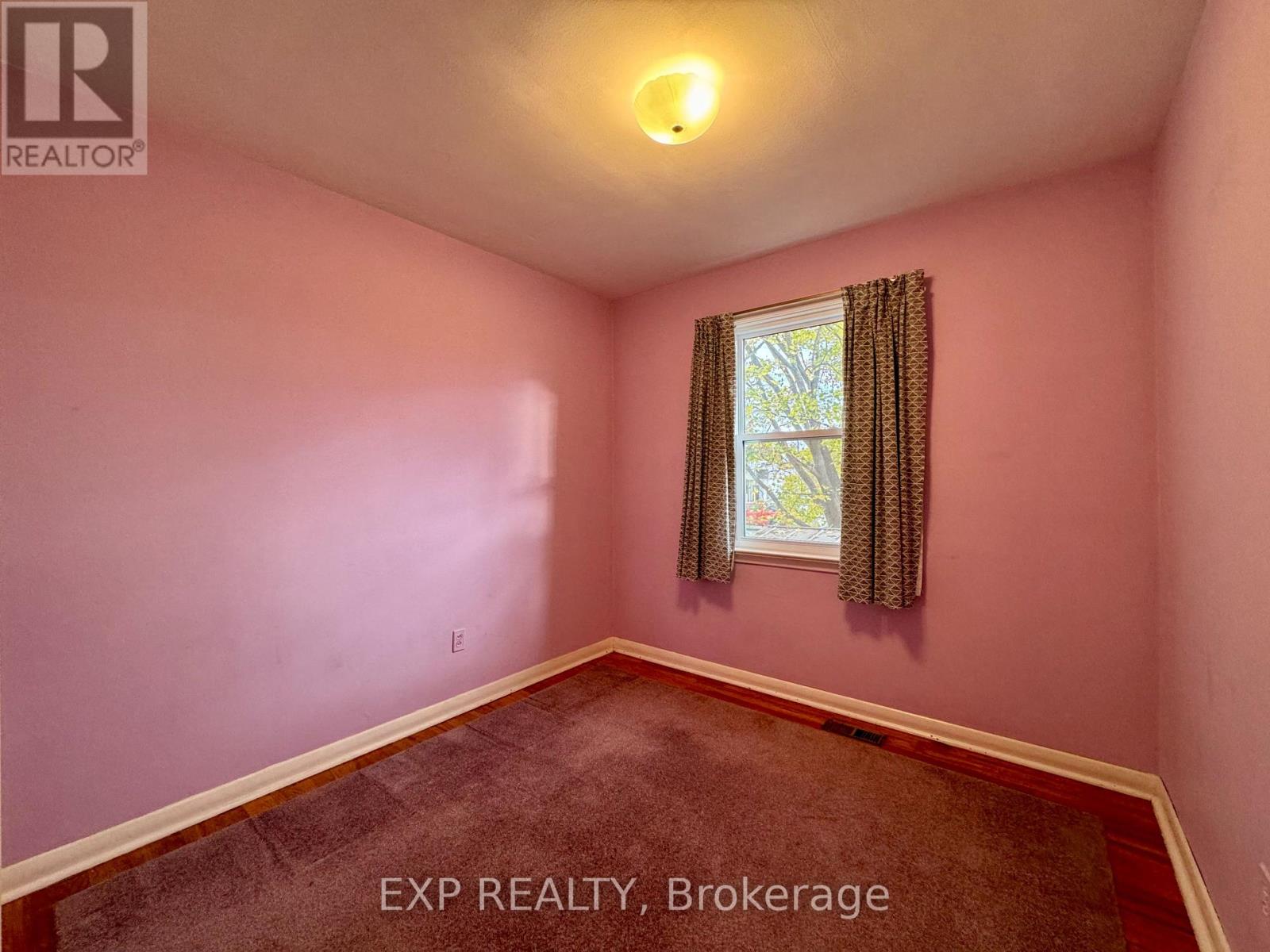A room with a window and a brown carpet.
