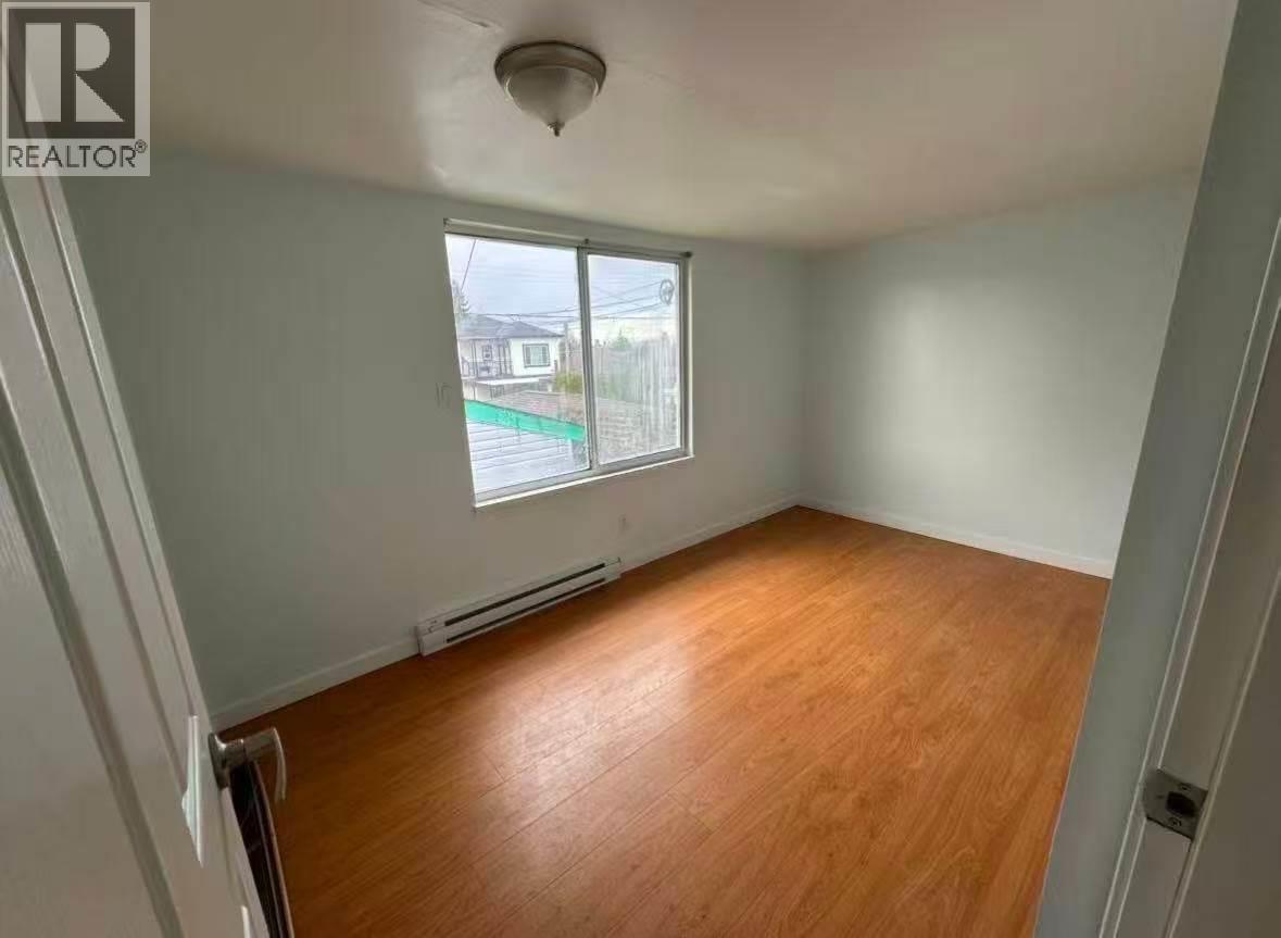 A room with wooden flooring and a window overlooking a street.