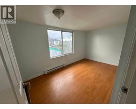 A room with wooden flooring and a window overlooking a street.