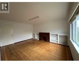 A large empty room with wooden floors and a fireplace.