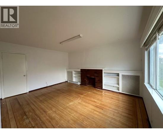 A large empty room with wooden floors and a fireplace.