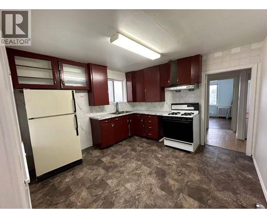 A kitchen with a refrigerator, sink, stove, and cabinets.