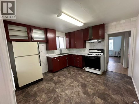 A kitchen with a refrigerator, sink, stove, and cabinets.