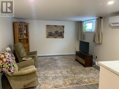 A living room with a brown chair and a painting on the wall.
