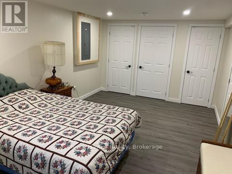 A bedroom with a bed, a nightstand with a lamp, and a wall-mounted mirror.