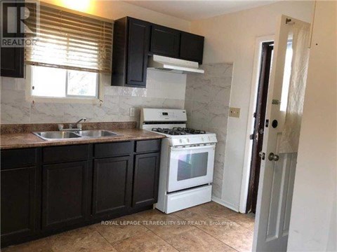 A kitchen with black cabinets and a white stove.