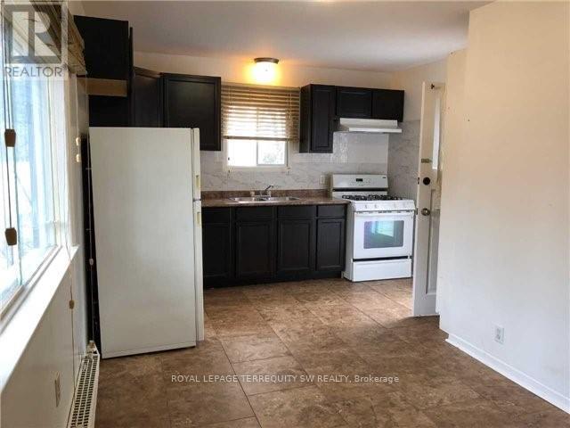 A kitchen with black cabinets and a white refrigerator.