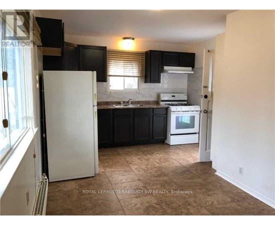 A kitchen with black cabinets and a white refrigerator.