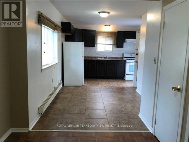 A kitchen with black cabinets and a white refrigerator.